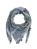A square scarf with a blue-gray base and a colorful zigzag pattern in pink, yellow, green, and orange, finished with gray fringe tassels, laid flat on a white fabric background.