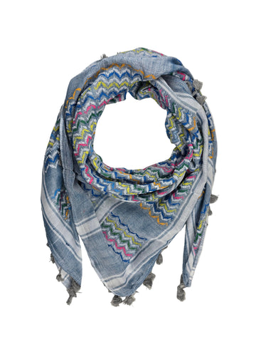 A square scarf with a blue-gray base and a colorful zigzag pattern in pink, yellow, green, and orange, finished with gray fringe tassels, laid flat on a white fabric background.