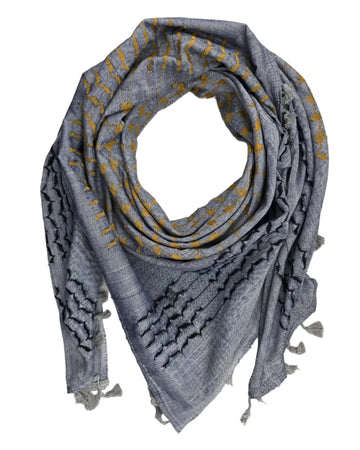 A gray woven scarf with yellow embroidered geometric patterns and frayed tassels, arranged in a loop on a white fabric background.