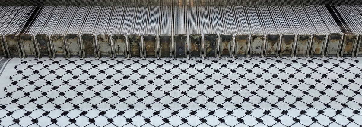 Textile being woven on a traditional loom with black and white pattern. Made in Palestine Keffiyehs